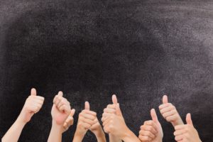 digital composite of multiple thumbs up on chalkboard background